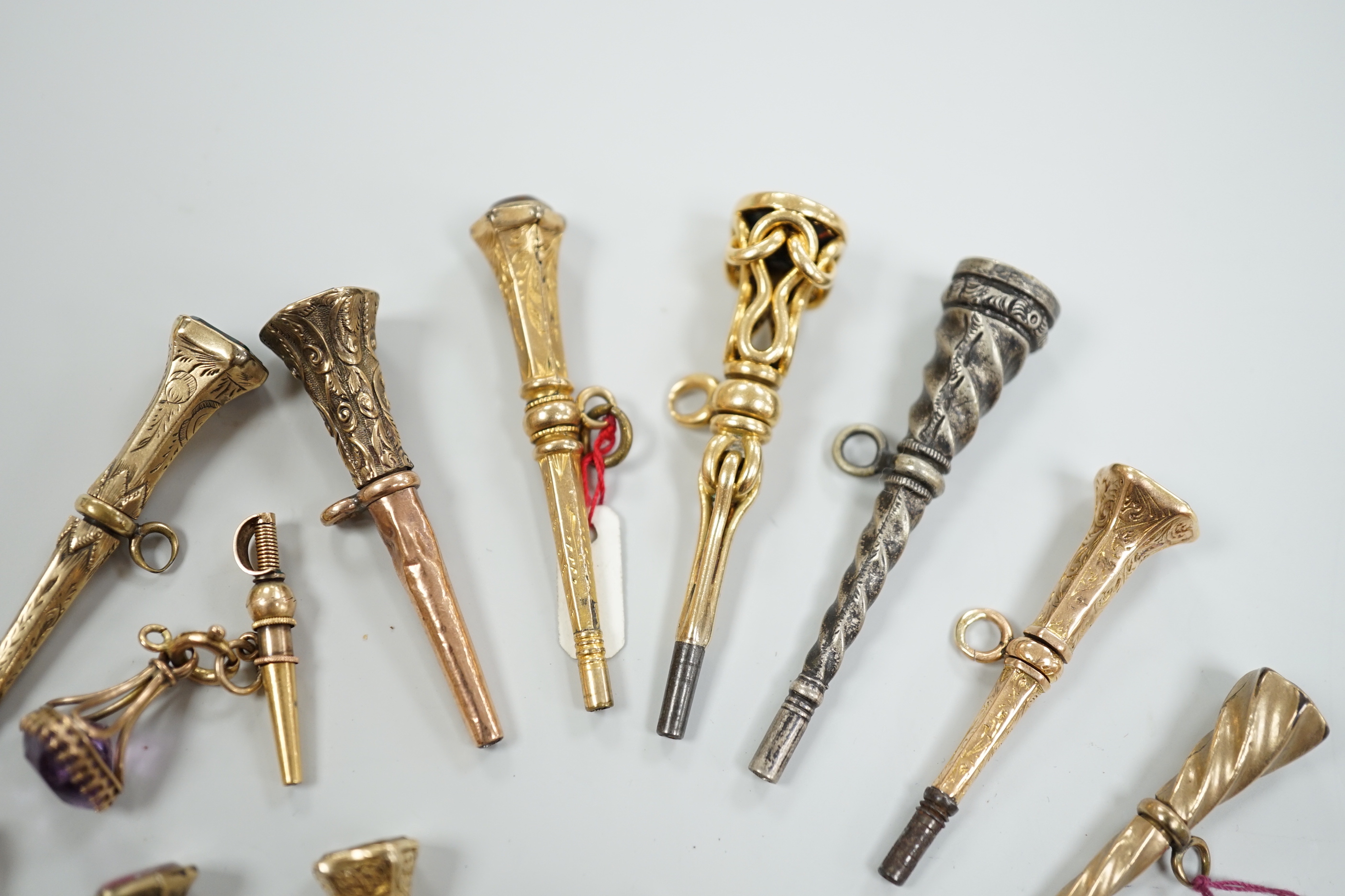 Fifteen assorted 19th century mainly yellow metal overlaid and gem set watch keys, including bloodstone, citrine and white chalcedony and one with enamel, mostly of trumpet form, largest 51mm.